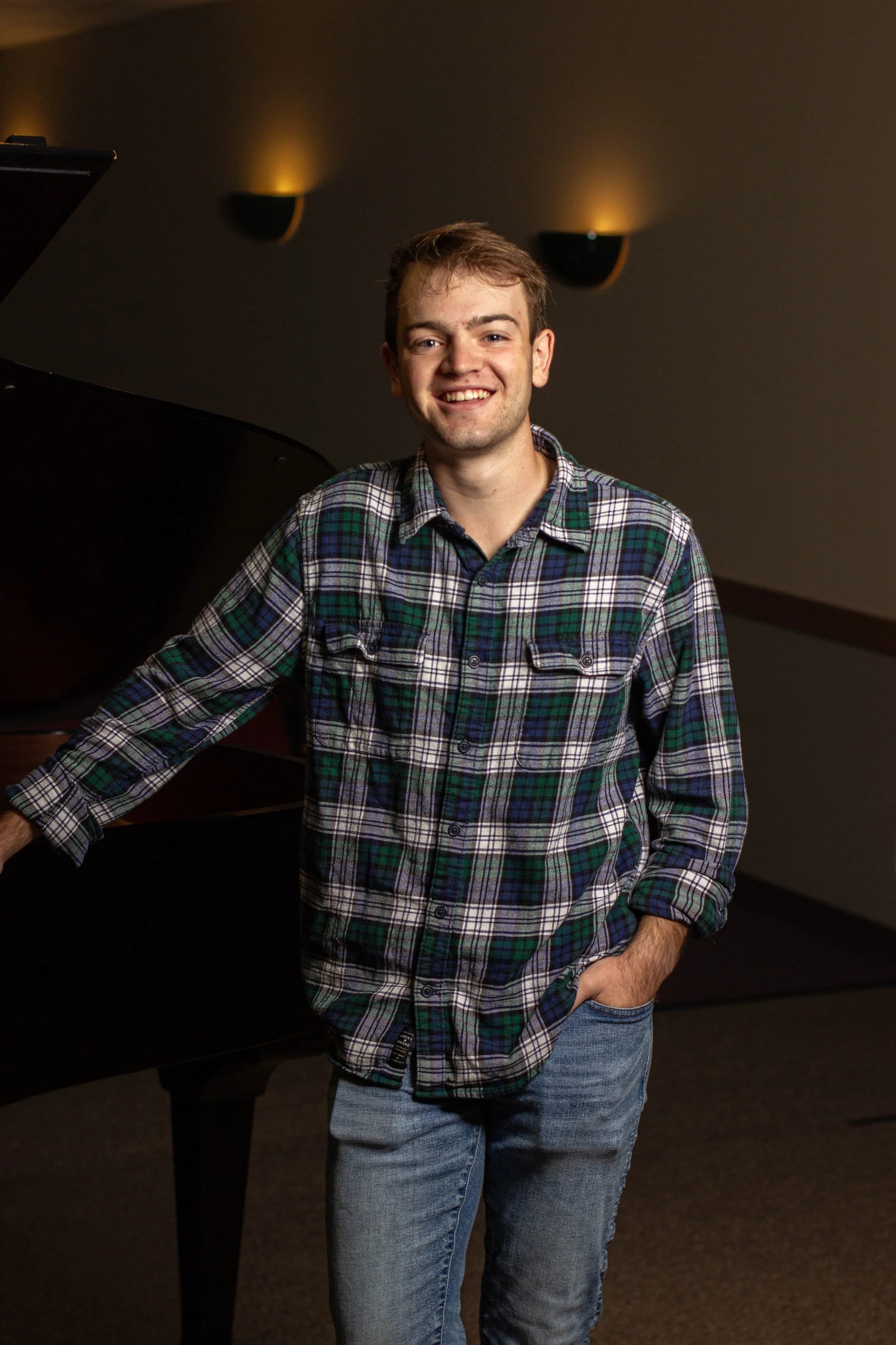 Portrait of Jake Kobler standing beside a piano.