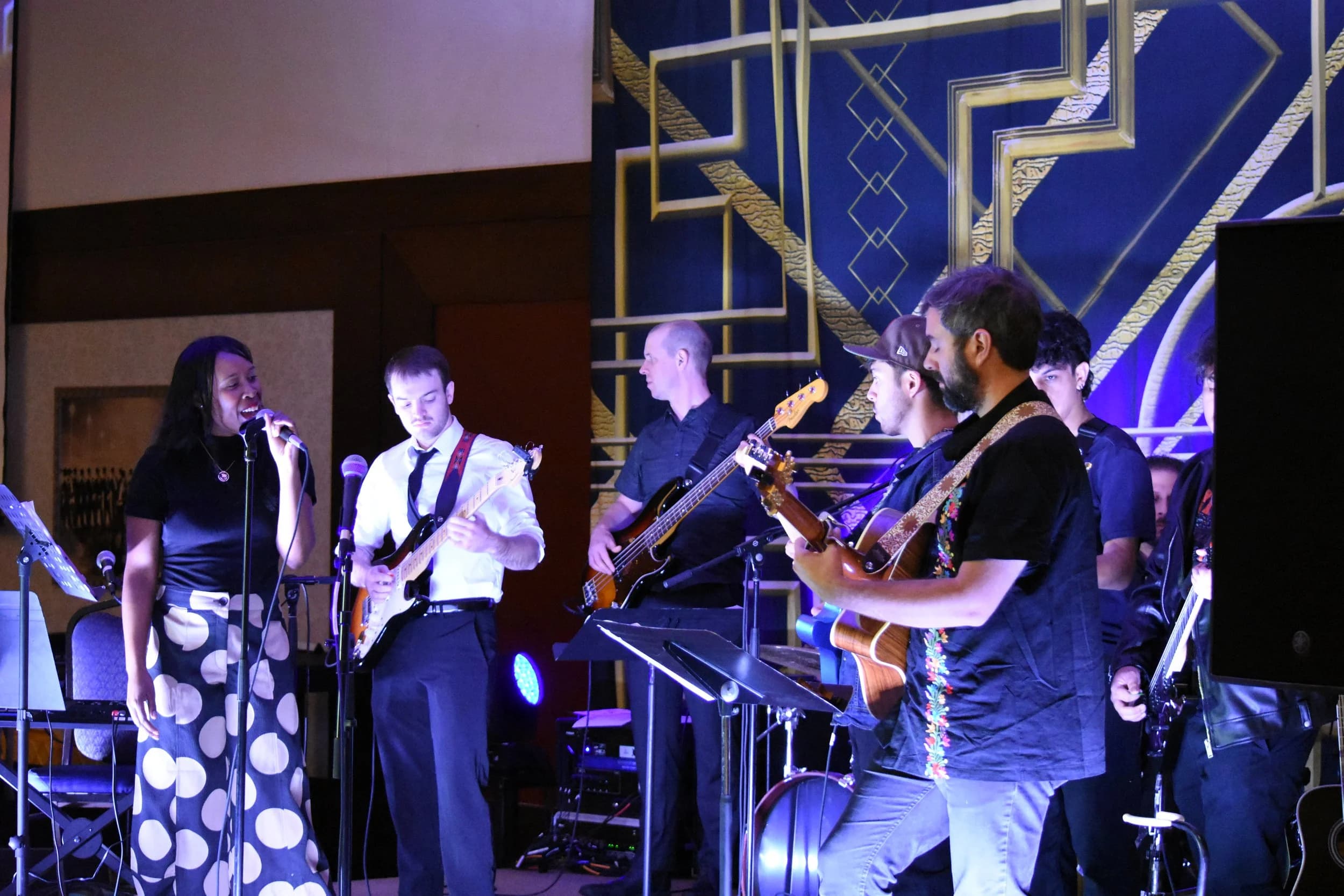 Jake Kobler performing with an ensemble in a lit ballroom setting.